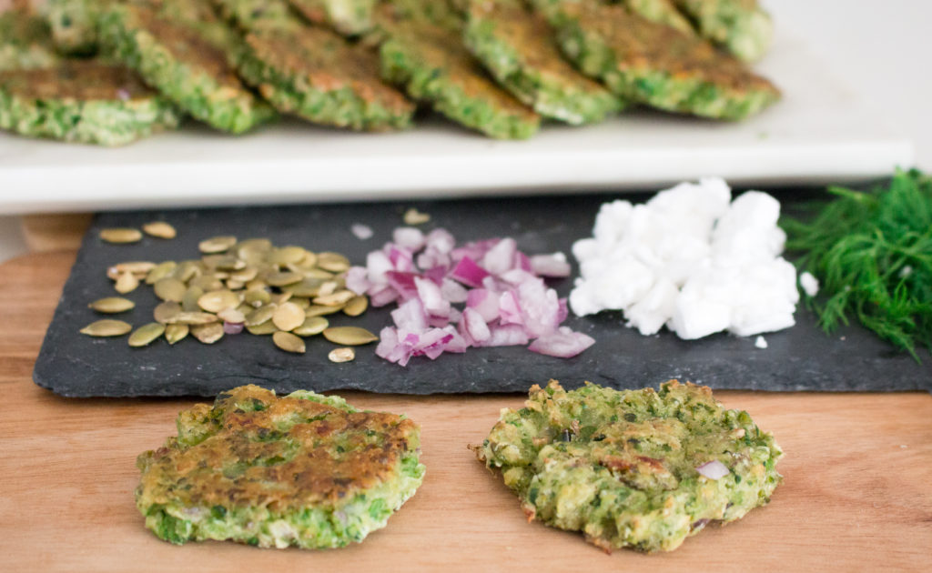 Two green pea fritters on fried and one baked on a slate plate