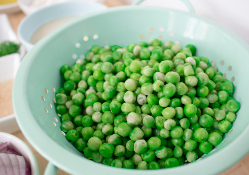 Green peas in a teal colander 
