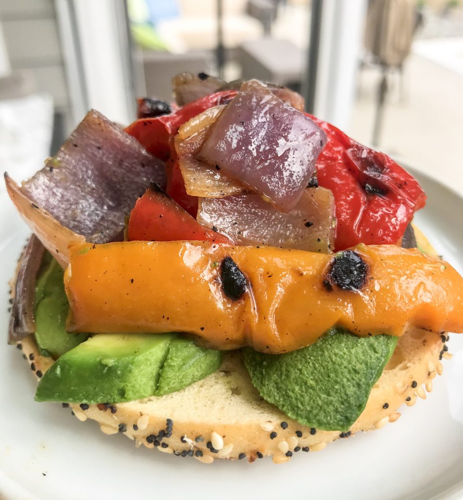 side view bagel with roasted peppers and avodaco