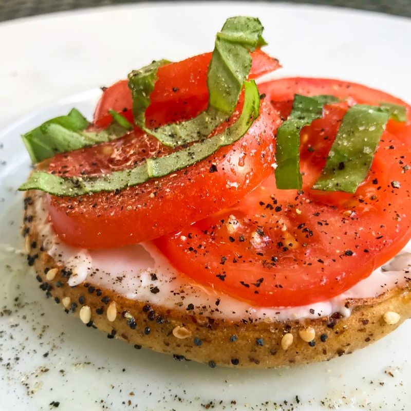 side view bagel with tomatoes and fresh basil