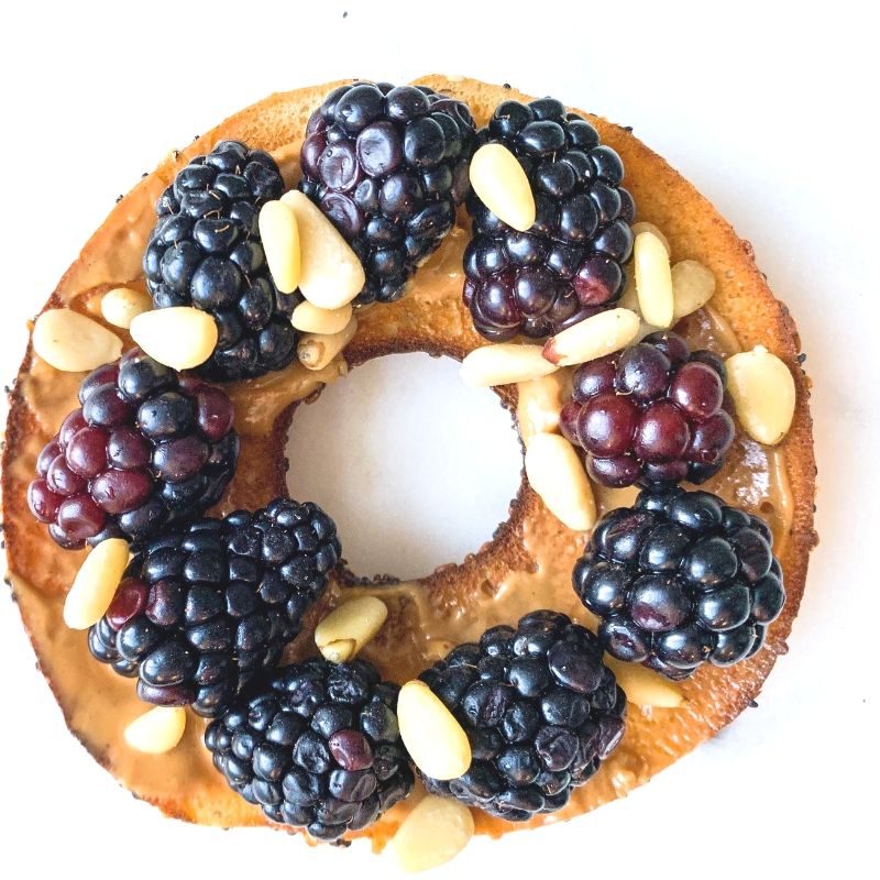 top view bagel with peanut butter, blackberries, raw pine nuts