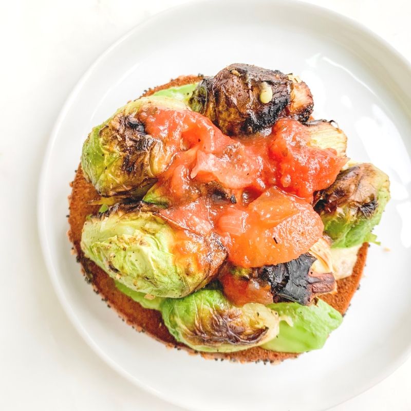 top view bagel with sliced avocado, charred brussel sprouts, fresh salsa